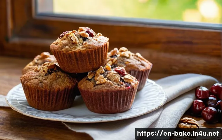 견과류와 과일이 포함된 제과 - A rustic kitchen scene featuring freshly baked walnut and dried cherry muffins arranged on a wooden ...